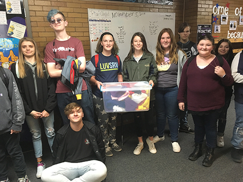 Group of students showing a tote filled with beanies they made.
